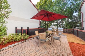 An outdoor patio with a red umbrella, brick flooring, and a grill. - Orlando Family Getaway | Resort Condo Minutes from Disney (Orlando)