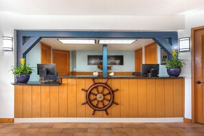 A reception desk with a ship's wheel, two potted plants, and a 'Welcome Home' sign. - Orlando Family Getaway | Resort Condo Minutes from Disney (Orlando)