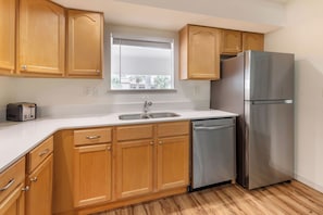 A kitchen with wooden cabinets, a stainless steel refrigerator, a dishwasher, and a window with blinds. - Orlando Family Getaway | Resort Condo Minutes from Disney (Orlando)