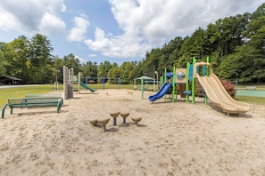Un'area giochi con scivoli e strutture per arrampicata, panchine e un’area con tavoli da picnic.