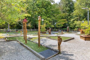 Un giardino con casette da uccelli in legno, una recinzione di legno e diversi alberi.