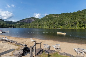 Une plage au bord du lac, avec des chaises longues et un quai.