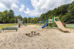 Ein Spielplatz mit Rutschen und Klettergerüsten, Bänken und einem Picknickbereich.