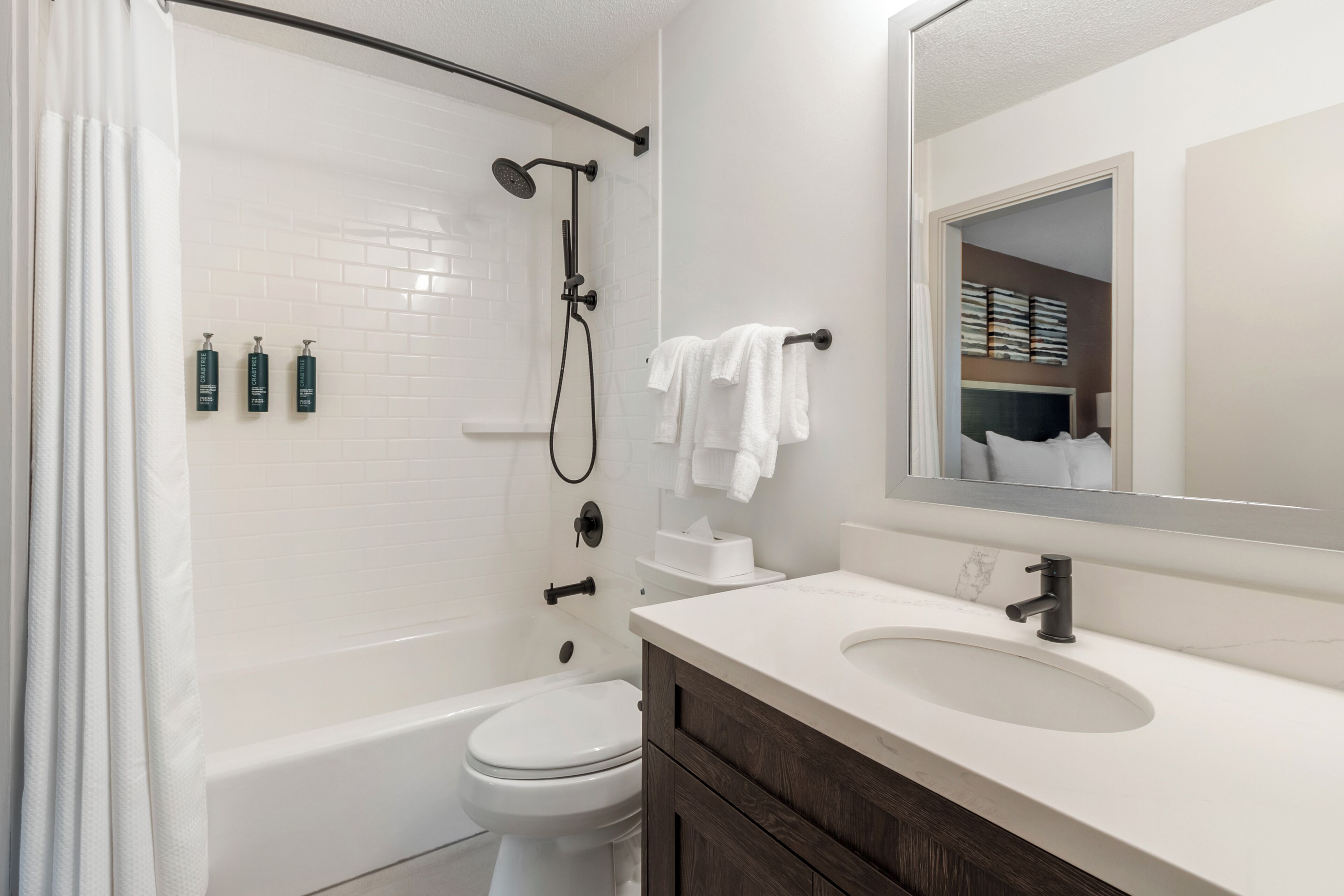 Une salle de bain moderne équipée d’une baignoire, de toilettes et d’un meuble-lavabo.