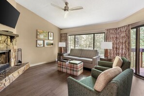 Ein Wohnzimmer mit Kamin aus Stein, einer Couch, einem Couchtisch und einem Fernseher.