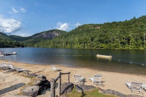 Une plage au bord du lac, avec des chaises longues et un quai.