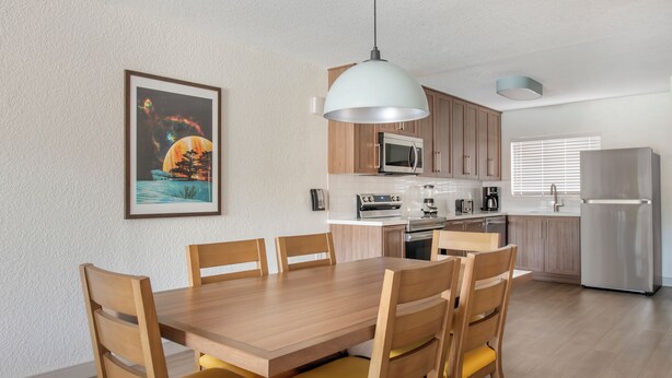 Een moderne keuken met een eettafel, stoelen en diverse apparaten.