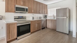 Een moderne keuken met houten kastjes, roestvrijstalen apparatuur en een wit aanrecht.