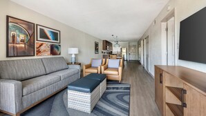 Een moderne woonkamer met een bank, stoelen, een salontafel en kunstwerken aan de wanden.