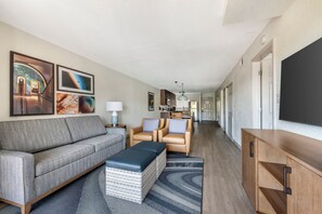 A modern living room with a sofa, chairs, a coffee table, and artwork on the walls. - Theme Parks, Pool Breaks & Happy Feet | Spacious Family 2BR (Kissimmee)