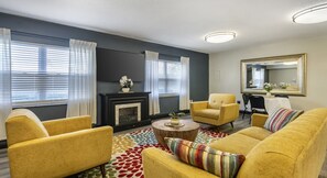 A living room with a fireplace, yellow armchairs, a round coffee table, and a colorful rug. - Disney Next Door, Family Time Everywhere | 2BR Resort Villa (Kissimmee)