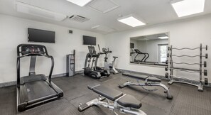 Een sportschool met loopbanden, elliptische trainers, een bankdrukpers en een gewichtrek.