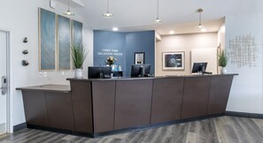 Een receptiebalie met een blauwe wand erachter, een kunstwerk in een lijst en een bord met de tekst 'ORBIT ONE VACATION VILLAS'.