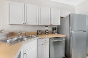 A kitchen with white cabinets, stainless steel appliances, a sink, and a dishwasher. - Spacious 2BR Resort Near Disney | Pool + Private Balcony (Kissimmee)