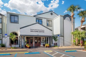 Een gebouw met een bord waarop 'Parkway International Resort Welcome Center' staat, en een parkeerplaats met aangegeven plaatsen.