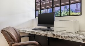 A workspace with a computer, keyboard, mouse, and printer on a marble countertop.