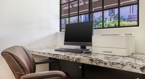 A workspace with a computer, keyboard, mouse, and printer on a marble countertop.
