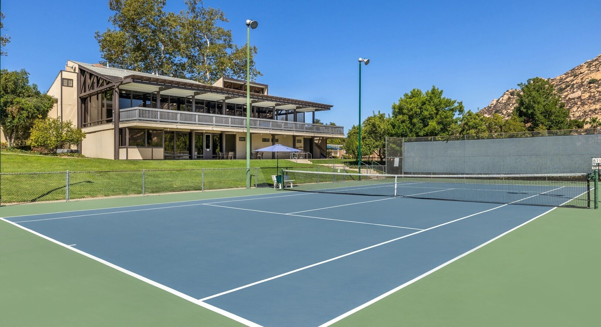 An outdoor tennis court with a building in the background.