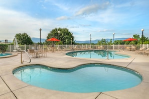 A pool area with two pools, lounge chairs, and umbrellas. - Relaxing 1BR Retreat Minutes from Dollywood (Pigeon Forge)