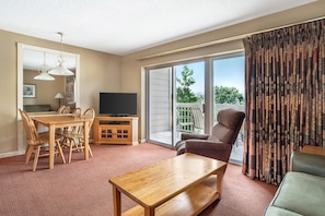 A living room with a wooden table, chairs, a sofa, a TV, and a sliding glass door to a balcony. - Relaxing 1BR Retreat Minutes from Dollywood (Pigeon Forge)