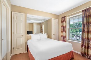 A hotel room with a large bed, a window with curtains, and a door. - Explore Pigeon Forge from This Cozy 1BR Retreat (Pigeon Forge)