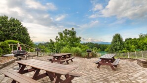 Un'area patio all'aperto con tavoli da picnic e barbecue.