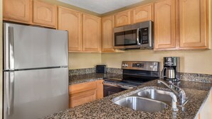 A kitchen with wooden cabinets, a stainless steel refrigerator, a microwave, a stove, and a sink. - Convenient 2BR Cottage Near Dollywood & Dining (Pigeon Forge)
