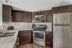 A modern kitchen with stainless steel appliances, dark wooden cabinets, and a white tiled backsplash. - Dollywood Adventures Start at This Spacious 2BR Retreat (Pigeon Forge)