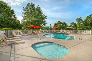 Ein Poolbereich mit zwei Pools, Liegestühlen und roten Sonnenschirmen.