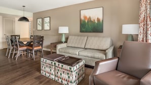 A living room with a sofa, a coffee table, a dining table with chairs, and a painting on the wall. - 2BR Getaway Minutes from Dollywood (Pigeon Forge)
