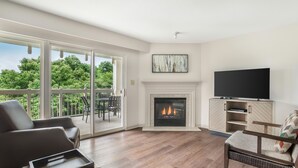 A living room with a fireplace, a television, and a balcony with outdoor furniture. - 2BR Getaway Minutes from Dollywood (Pigeon Forge)