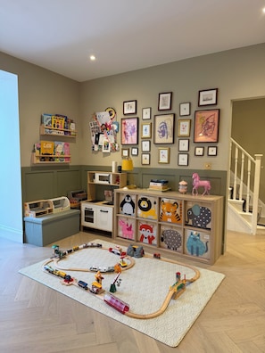 A child's playroom with a train set on a patterned rug, shelves with books and toys, and framed artwork on the wall. - Spacious 3-bedroom house in a wonderful London neighborhood (London)