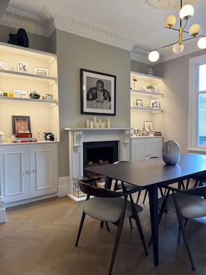 A dining area with a fireplace, wooden flooring, and a chandelier. - Spacious 3-bedroom house in a wonderful London neighborhood (London)