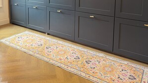 Ein großer Kleiderschrank mit mehreren Türen und Schubladen, ein gemustertes Teppich und Holzdielen.