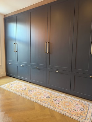 A large wardrobe with multiple doors and drawers, a patterned rug on the floor, and wooden flooring. - Spacious 3-bedroom house in a wonderful London neighborhood (London)