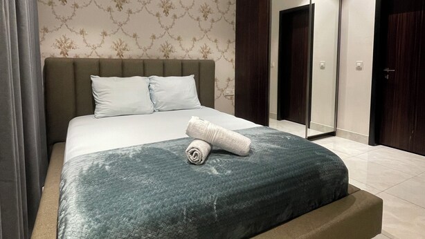 Ein modernes Schlafzimmer mit einem großen Bett, einem Spiegel und einer Tür.