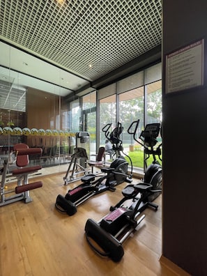 A gym with various exercise equipment, large windows, and a visible exit sign. - Luxury 2-Bedrooms Apartment in Airport Residential (Accra)