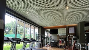 Ein Fitnessstudio mit Laufbändern, Kraftgeräten und einem großen Fenster mit Blick auf Grünflächen.
