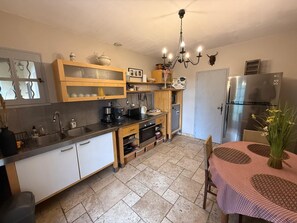 A kitchen with a refrigerator, stove, sink, and wooden cabinets. - Air-conditioned villa with a pool at the foot of the Luberon (Mérindol)