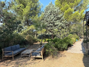 Ein Garten mit einer Holzbank, einer Couch und einem Weg, der zu einem Gebäude führt.