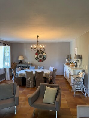 Ein Essbereich mit einer Chandelüster, einem runden Tisch und Stühlen.
