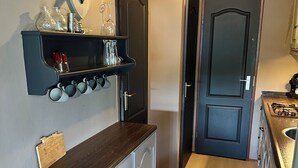 Een smalle gang met een keukenhoek aan de ene kant, met een houten aanrecht, kasten en een opgehangen decoratie van een hertenkop.