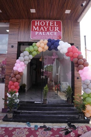 A hotel entrance with a sign reading 'HOTEL MAYUR PALACE' and a colorful balloon arch.