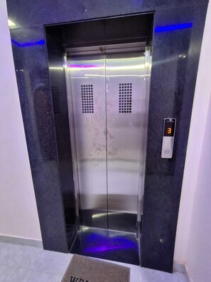 An elevator with a digital display showing the number 3, a metallic finish, and a blue light strip on the wall.