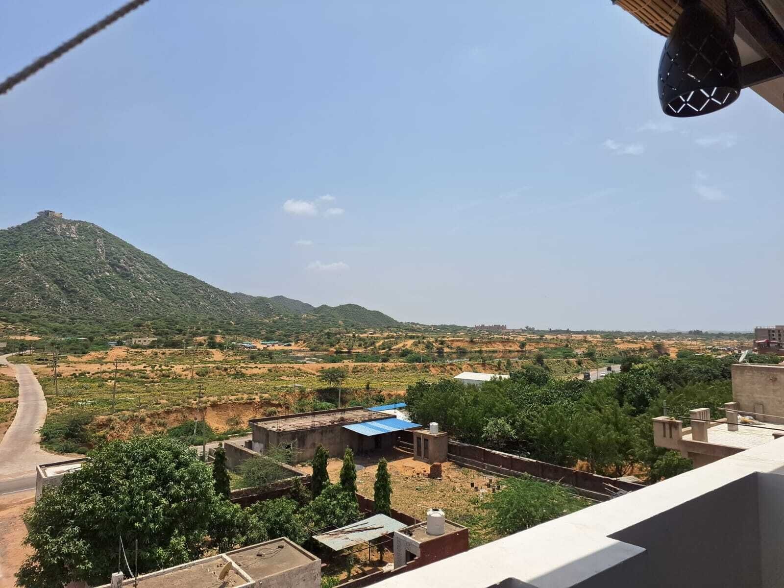 Una zona residenziale con una collina in evidenza sullo sfondo, una strada che serpeggia nel paesaggio e edifici con tetti piani.