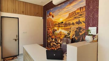 Mostrador de recepción con una laptop, una planta en maceta y un aire acondicionado de pared.