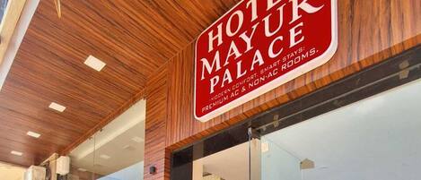 A hotel entrance with a sign reading 'HOTEL MAYUR PALACE' and a reception desk visible inside.