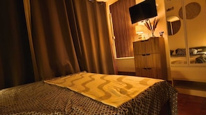 A hotel room with a bed, a TV, a wardrobe, and a bedside table with a lamp. - Studio Soleil Bleu - Within walking distance of the Port Plages Center (Agde)
