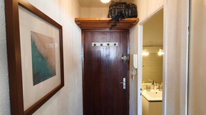 Eine Holztür mit kleinem Fenster, ein gerahmtes Bild an der Wand und ein durchgegangenes Badezimmer.