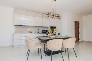 Een moderne keuken met witte kasten, een centraal eiland en een eethoek met vier stoelen.